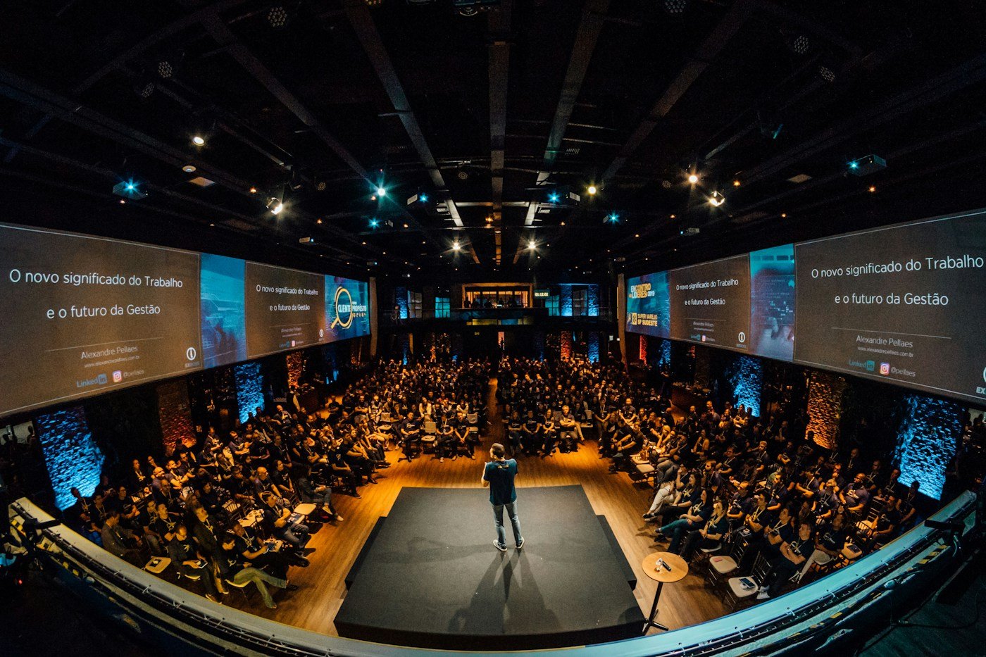 A speaker seen from behind facing an audience